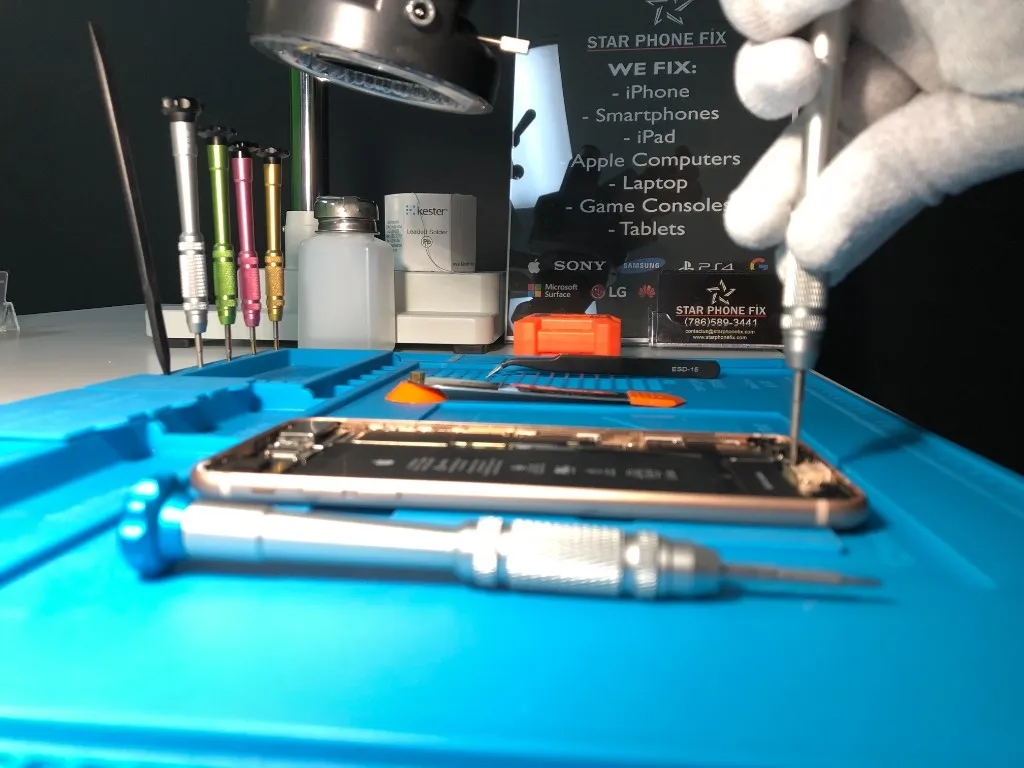 Technician repairing an opened iPhone on a Star Phone Fix workbench with precision tools