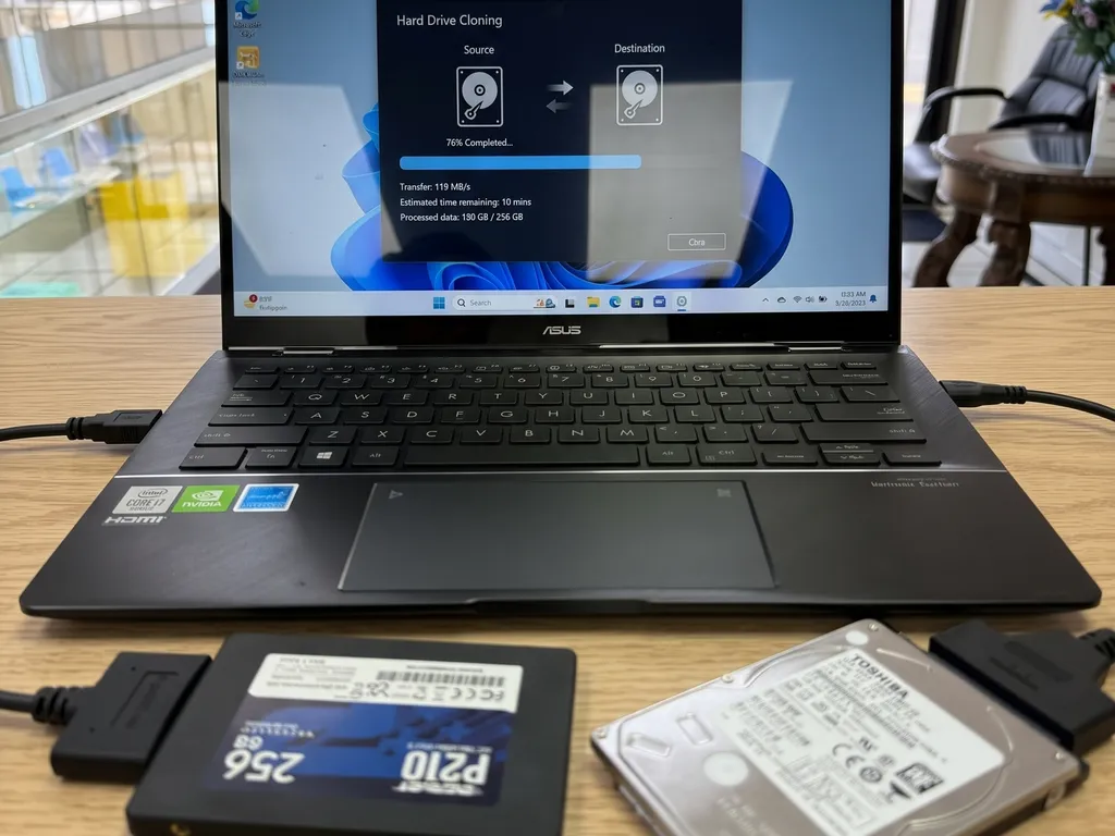 Laptop ASUS con un programa de clonación copiando un disco duro Toshiba a un SSD de 256GB mediante adaptadores USB