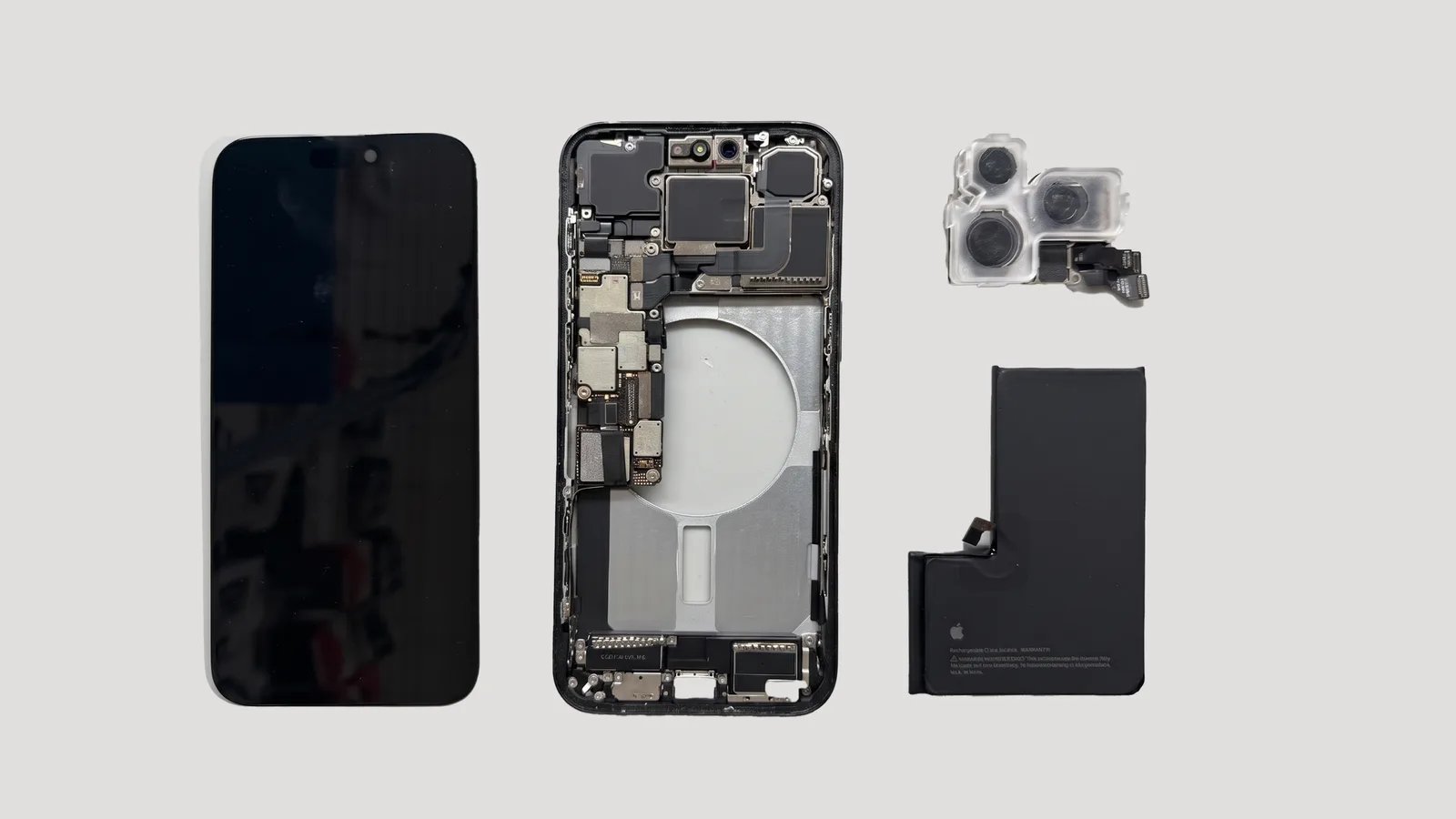 iPhone desarmado con su pantalla, el módulo de cámaras traseras y la batería sobre una superficie gris claro