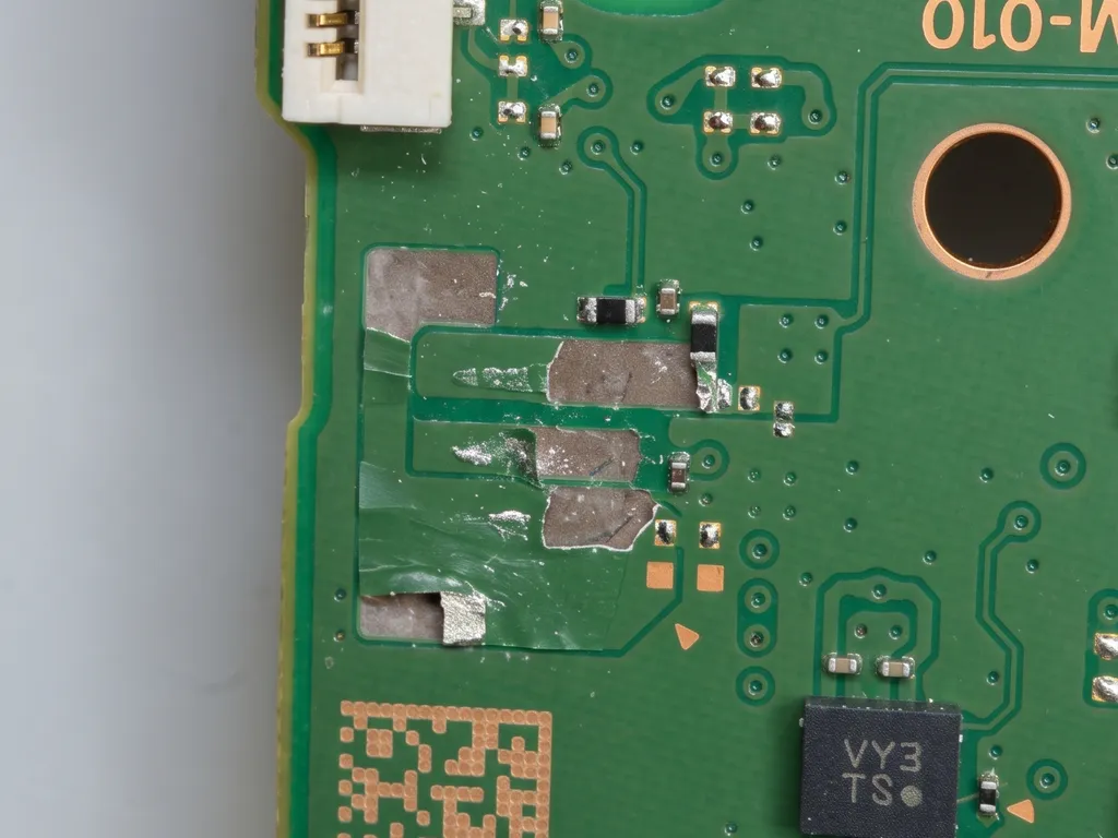 Placa de un control DualSense de PS5 con los pads de soldadura arrancados donde estaba el conector de batería
